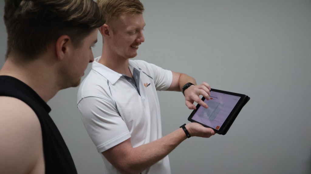 Physiotherapist demonstrating sports testing on tablet