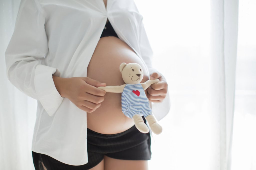Pregnant woman holding teddy
