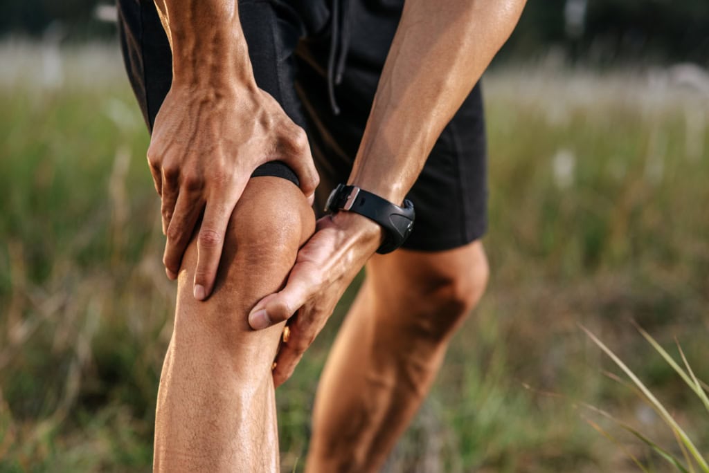 A man clutching his knee with pain